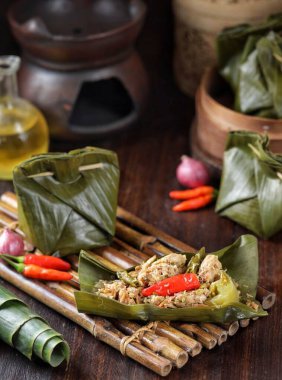 Tahta yüzeyde içi doldurulmuş yeşil yapraklarla dolu lezzetli bambu buharı.