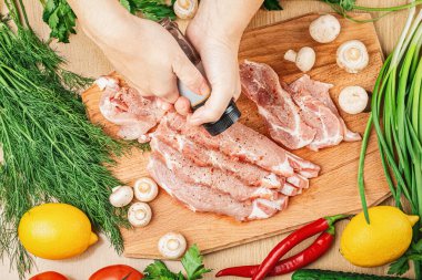 Baharat doğrama ve ahşap kesim tahtasına domuz pirzolası serpiştirme işlemi dereotlu, maydanozlu, mantarlı, limonlu, acı biberli. Yukarıdan görüntüle.