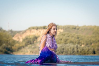 Nehir kıyısında deniz kızı kuyruklu bir kız. Mistik ve peri masalı kahramanı. Tatildeki bir sansasyon. Su temizlendi.