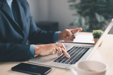 Modern masa başında dizüstü bilgisayar ve akıllı telefon, kahve fincanı ve yakın zamanda cep telefonu ve verimliliği sembolize eden yumuşak gün ışığında not içeren mesleki çoklu görev..