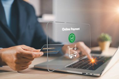 Bilgisayarda yazarken online ödeme yapan adam, kalkan simgesi ve el arabası ile ekommerce kontrol arayüzü, nakitsiz alışveriş ve bankacılık hizmetleri için dijital fintech işlemi.
