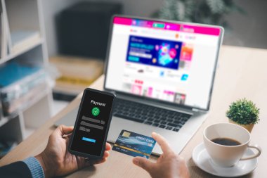 İnternetten kredi kartı ve akıllı telefon ödeme uygulaması ile ev ofis masasında dizüstü bilgisayarın yanında alışveriş, ekommerce hesabı için güvenli dijital işlem, fintech bankacılık, nakitsiz alım, modern yaşam tarzı.