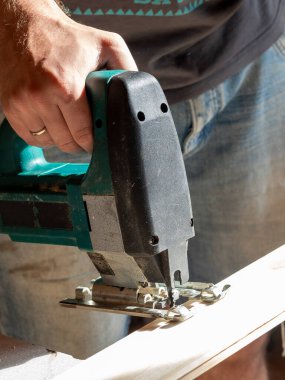 Tahta tahtayı elektrikli testereyle kesen bir işçinin yakın çekimi.