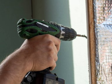 Bir adam bir tornavida tutuyor ve vidayı alçıpana sıkıştırıyor. seçici odak