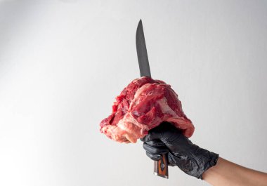 Beyaz arka planda izole edilmiş bir bıçakla saplanmış çiğ et parçası. Uzayı kopyala, ön görünüm. Taze et.