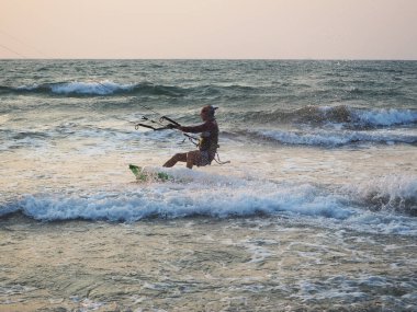 Hindistan, Goa, Arambol, gün batımında kıyıda uçurtma uçuran bir adam.