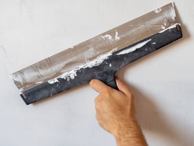 Duvarda çalışan uzun bir spatulası olan bir işçinin eli. İç işleri, inşaat konsepti