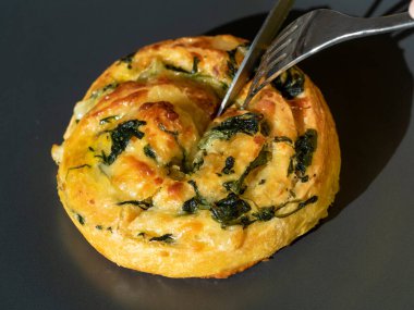 Ispanaklı ve peynirli hamur işi bıçak ve çatalla kesilir. Yan görünüm, yakın plan