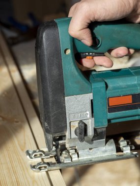 Tahta tahtayı elektrikli testereyle kesen bir işçinin yakın çekimi.