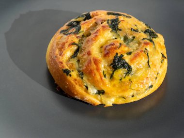 Esmer arka planda ıspanaklı ve peynirli hamur işi. Yan görünüm, yakın plan