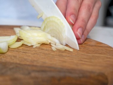 Beyaz soğanlar tahta bir tahtanın üzerinde bıçakla kesilir. Yemek pişirme kavramı. Seçici odak.