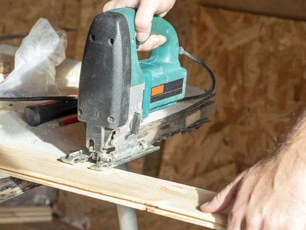 Tahta tahtayı elektrikli testereyle kesen bir işçinin yakın çekimi.