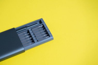 Sarı arka planda bir çantada parçaları olan bir tornavida seti. Kopyalama alanı, çalışma araçları