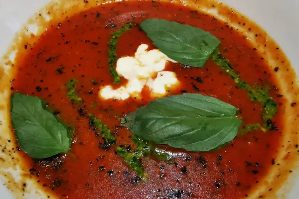 バジルの葉で飾られた白いプレートにStracciatellaチーズとイタリアのトマトスープ — ストック写真