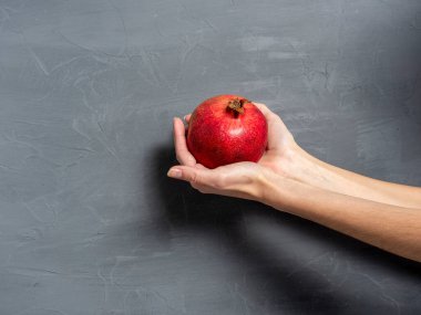 Gri desenli arka planda parlak, olgun, kırmızı bir nar.