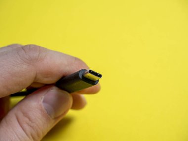 Erkek eli usb tipi C kablosu sarı arka planda yakın plan. Boşluğu kopyala