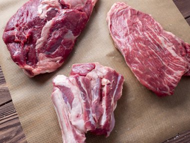 Üç parça taze çiğ et parşömen üzerine yayılır. Üst manzara, düz yatış. tahta arkaplan