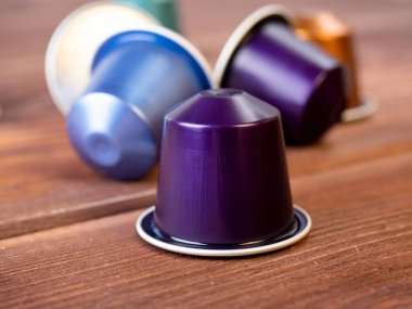 Ahşap zemin üzerinde aromatik öğütülmüş kahve bulunan alüminyum kapsüller. ön görünüm