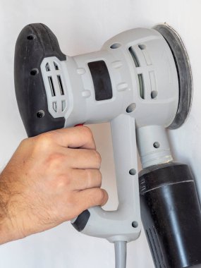 Bir mimar beyaz beton duvarı işlemek için zımpara makinesi kullanır. İnşaat konseri