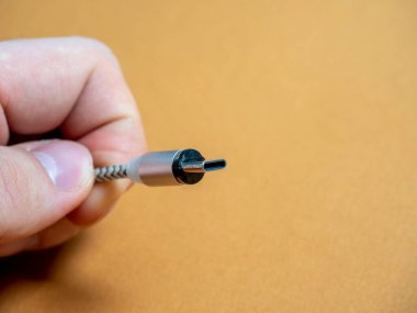 USB tip C kablosu, elinizde kahverengi bir fonda manyetik bir eklenti ile katlanabilir. Boşluğu kopyala