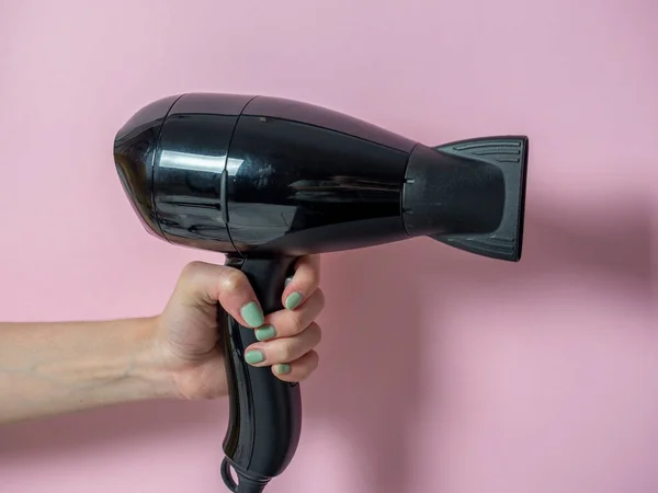 Mão segurando o secador de cabelo isolado no fundo branco