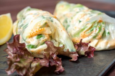 Siyah desenli bir tabakta yuvarlanmış börekler var. Lezzetli bir diyet. Asya mutfağı, kapatın.