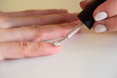 Tırnağa beyaz oje sürüyorum. Evde manikür. Tırnak cilası fırçası