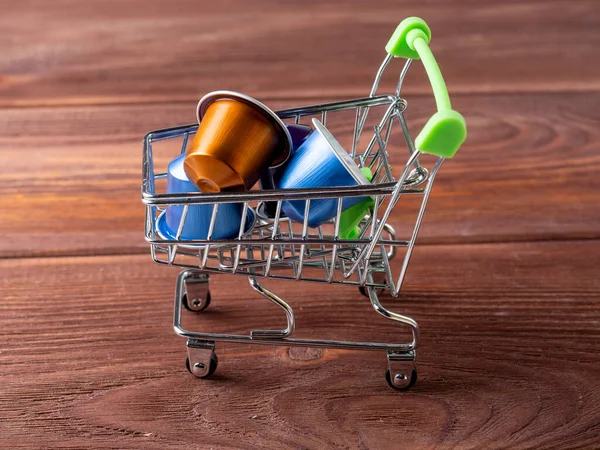 Renkli alüminyum kapsüllerle ve aromatik öğütülmüş kahveyle dolu küçük bir market arabası. Modern kahve depolama ve hazırlama teknolojileri