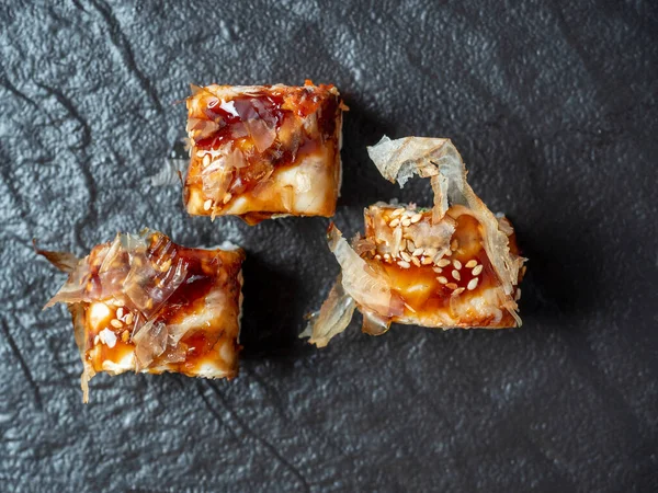 Dokulu siyah tabakların üzerine serilmiş lezzetli dürümlerin yakın çekimi. Üst manzara, düz yatış. Japon mutfağı.