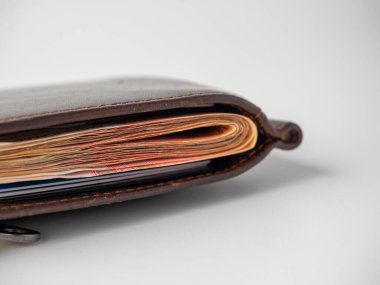 Beyaz arka planda banknotlarla dolu kahverengi deri bir cüzdanın yakın çekimi. Zenginlik, kâr, zenginlik kavramı