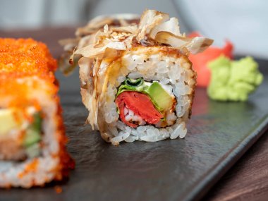 Siyah bir tabakta suşi rulosunun yakın çekimi. Geleneksel Japon mutfağı