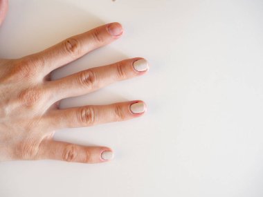 Beyaz arka planda kısmen boyanmış tırnakları olan bir kadın eli. Manikür konsepti. kozmetoloji