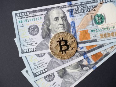 yellow bitcoin lies on hundred-dollar bills. The concept of cryptocurrency, investment, income. Top view, black background