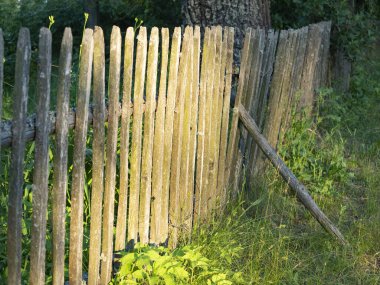 Akşam güneş batarken kırsalda eski bir ahşap çitin yakın çekimi. Köy manzarası.