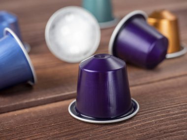 Kahverengi ahşap zemin üzerinde kahve olan parlak renkli kapsüller. Yaklaş, kenar görünüm