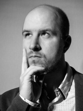 Black and white Portrait of a middle-aged man in a jacket and shirt, who looks thoughtfully to the side, pressing a finger to his cheek, beard, a little hair on his head, Caucasian