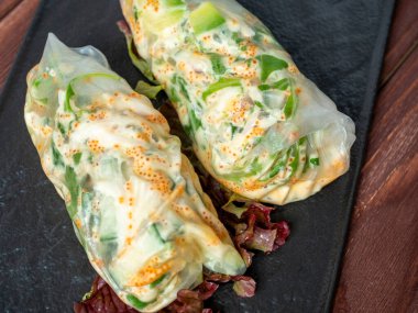 Siyah desenli bir tabakta yuvarlanmış börekler var. Lezzetli bir diyet. Asya mutfağı, kapatın.