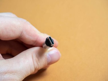 USB tip C kablosu, elinizde kahverengi bir fonda manyetik bir eklenti ile katlanabilir. Boşluğu kopyala