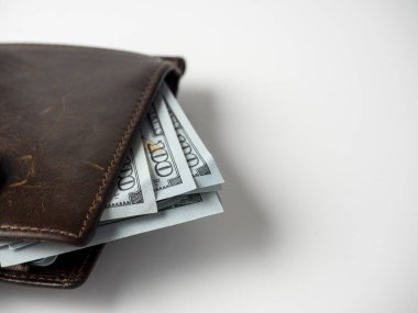 Beyaz arka planda dolar banknotlarıyla doldurulmuş kahverengi deri bir cüzdanın yakın çekimi. Zenginlik, kâr, zenginlik kavramı. Boşluğu kopyala