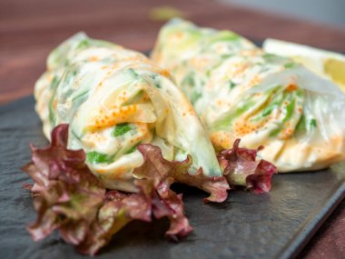 Siyah desenli bir tabakta yuvarlanmış börekler var. Lezzetli bir diyet. Asya mutfağı, kapatın.