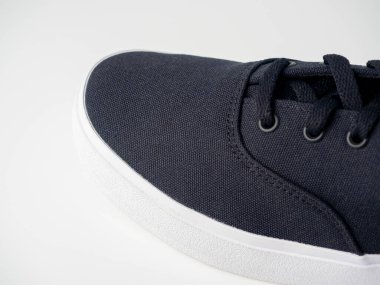 Siyah tuval spor ayakkabılarının yakın çekim kısmı beyaz arka planda izole edilmiş. Prokukt çekimi, yan görünüm