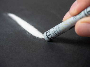 100 dolarlık banknotun yakın plan çekimi beyaz toz çizgisinin üzerinde bir tüpe sarıldı. Kötü alışkanlıklar, uyuşturucu kullanımı, ölüme yol açan yasadışı maddeler. Seçici Odaklanma