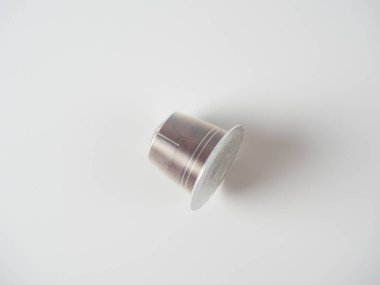 Beyaz arka planda öğütülmüş kahvesi olan plastik bir kapsül. Yeniden kullanılamayacak çevre dostu olmayan paketleme