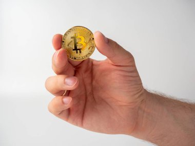 Elinde altın renkli bir bitcoin tutan bir adamın yakın çekimi. Beyaz arkaplan, Kripto Para Birimi Kavramı