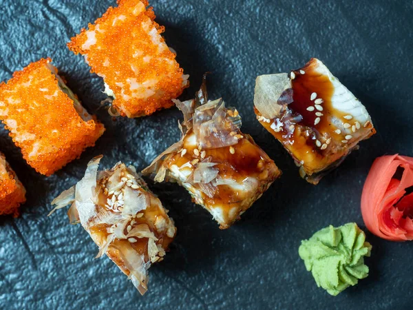 Suşili yemek kompozisyonu. Siyah tabakta, zencefil ve wasabi turşusunun yanında çeşit çeşit suşi. Üst manzara, düz uzanma