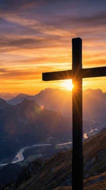 Canlı bir günbatımı gökyüzüne karşı siluetlenmiş güçlü bir haç görüntüsü görkemli bir dağ sırasına ve dolambaçlı bir nehre bakan umut ve inancı sembolize eden..