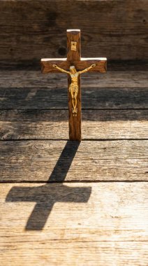 İsa 'nın figürünün yer aldığı ahşap bir haç, ahşap bir arka planda belirgin bir şekilde sergileniyor ve uzun, dramatik bir gölge oluşturuyor. Doğal ışık, tahtanın dokusunu vurgular..