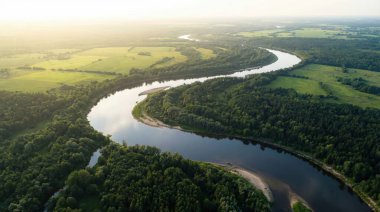 Soluk kesici bir hava perspektifi, kıvrımlı bir nehri yakalar ve yoğun yeşil ormanlar ve açık araziler boyunca uzanan yolunu zarifçe oyar. Hepsi de batan güneşin sıcak, altın parıltısıyla yıkanır. Sahne bir huzur hissi uyandırıyor.