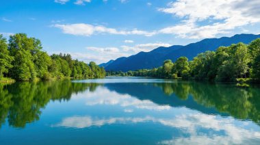 Sakin bir dağ gölü canlı mavi gökyüzünü, kabarık beyaz bulutları ve yoğun yeşil ormanı mükemmel bir şekilde yansıtıyor, çarpıcı ve huzurlu bir doğal manzara yaratıyor..
