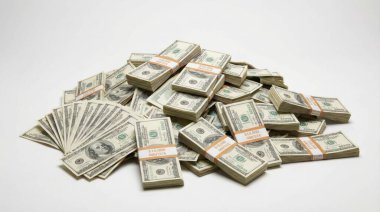 Büyük miktarda Amerikan doları banknotları, hem gevşek hem de düzgünce paketlenmiş desteler halinde, temiz beyaz bir arkaplan karşısında zenginlik, finans ve ekonomik refahın görsel bir temsili oluşturur.